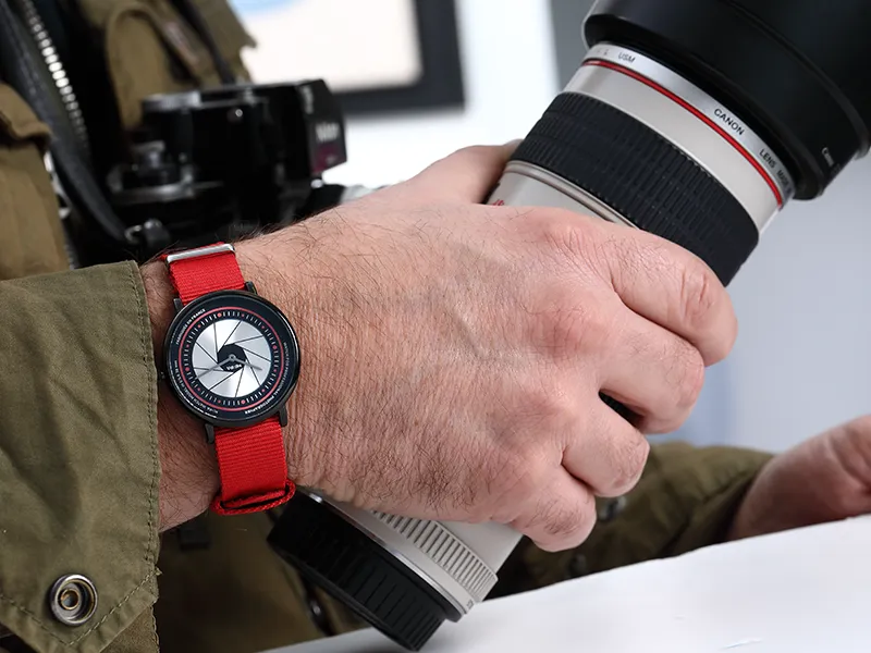 Montre portée par un photographe tenant un appareil photo