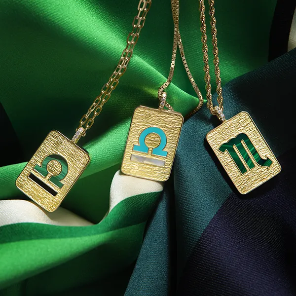 Trois pendentifs signes du zodiaque en or sur tissu vert